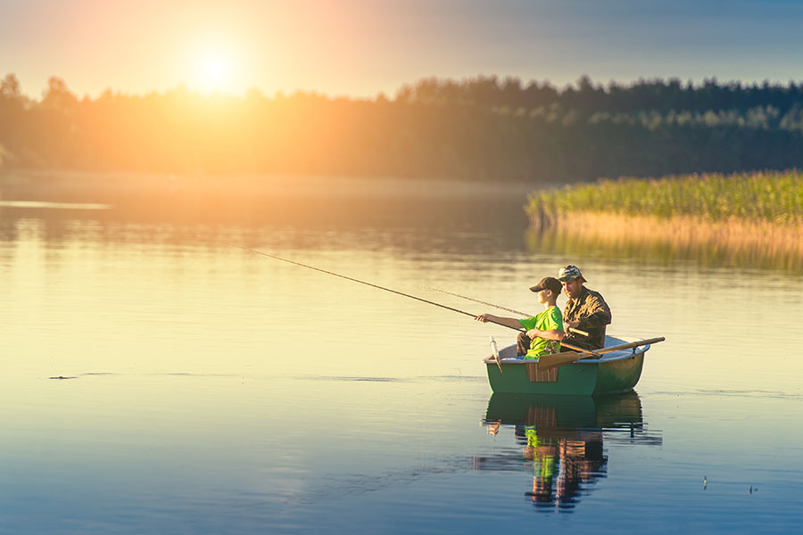 Padre e hijo pescando desde un bote al atardecer