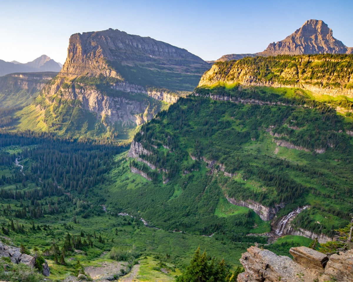 The sun shines on the grassy hills of Glacier National Park 