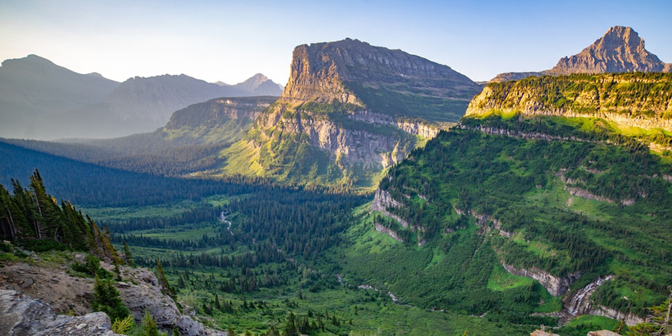 The sun shines on the grassy hills of Glacier National Park 