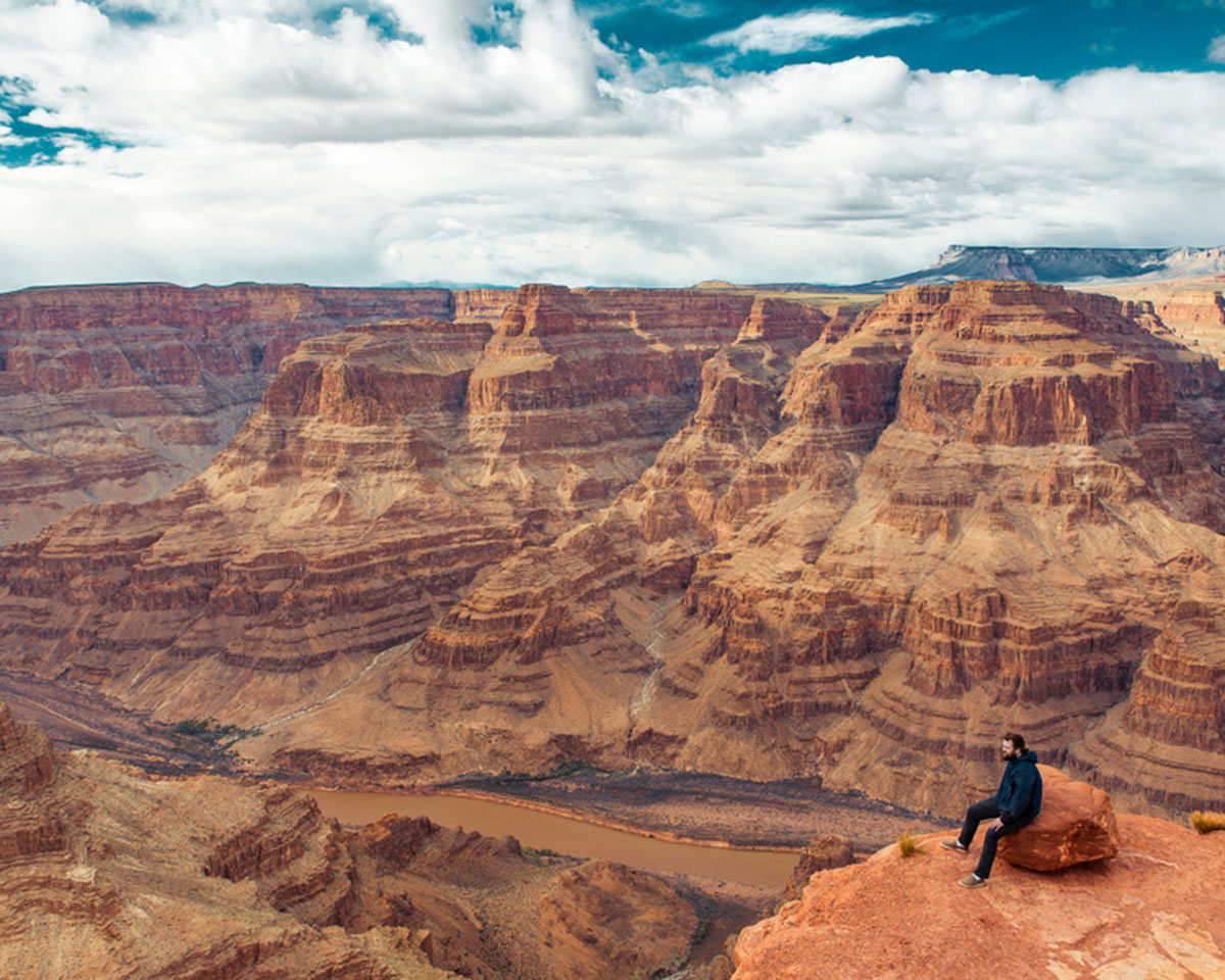 A hiker sits on the edge of the Grand Canyon