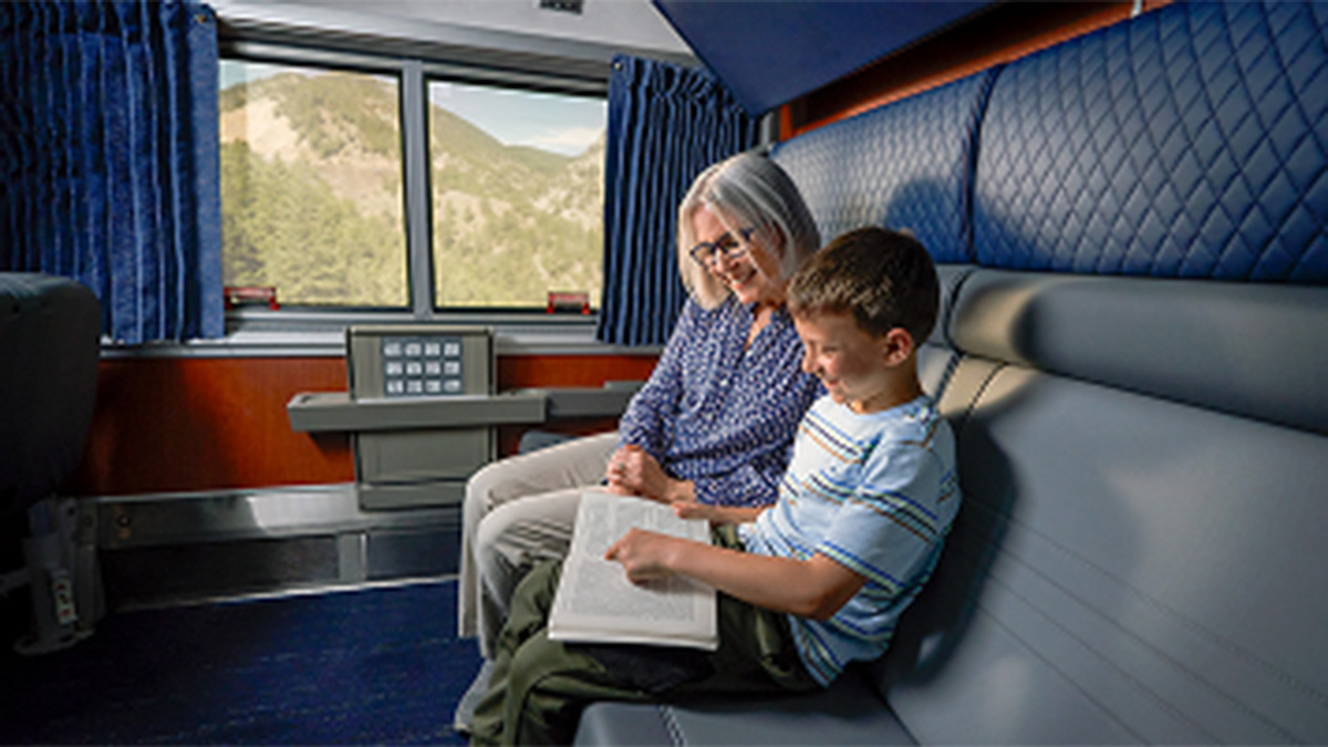 An older woman and a child read a book in a private train room