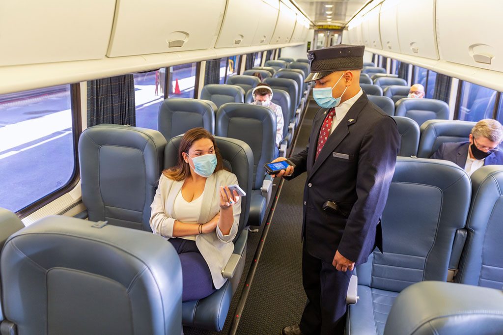 Conductor scanning a passenger's ticket on a mobile device.