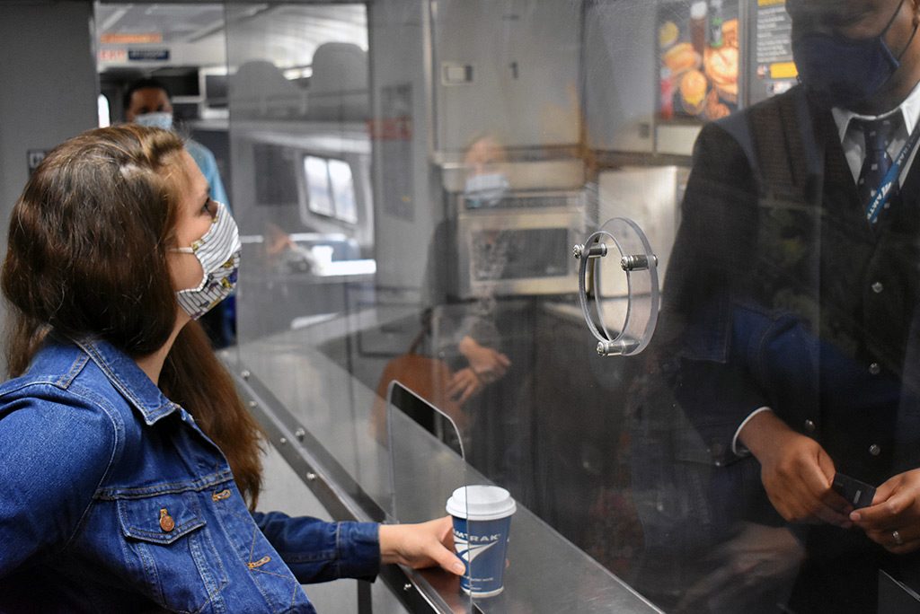 Customer making purchase in cafe car with plexiglass separating attendant.