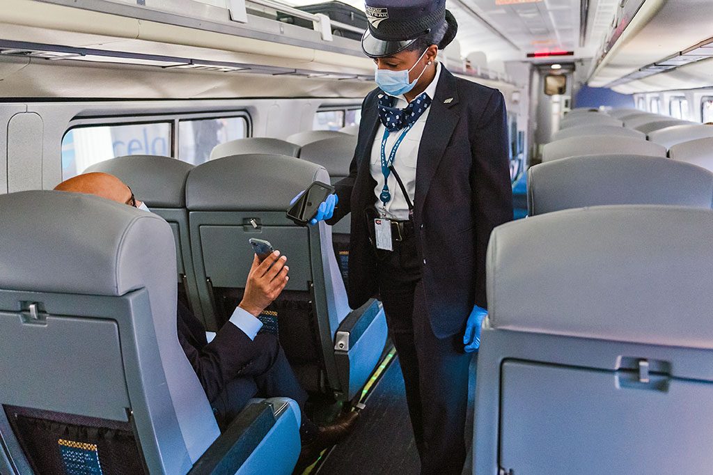 Conductor scanning customer's ticket on a mobile phone.