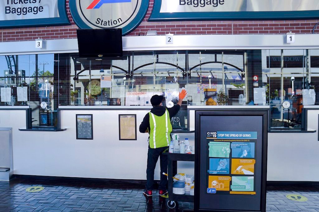Station staff cleaning ticket office window.