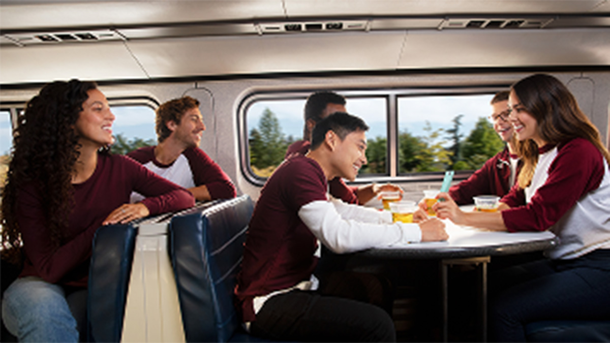 Students laugh and talk in a train's cafe car