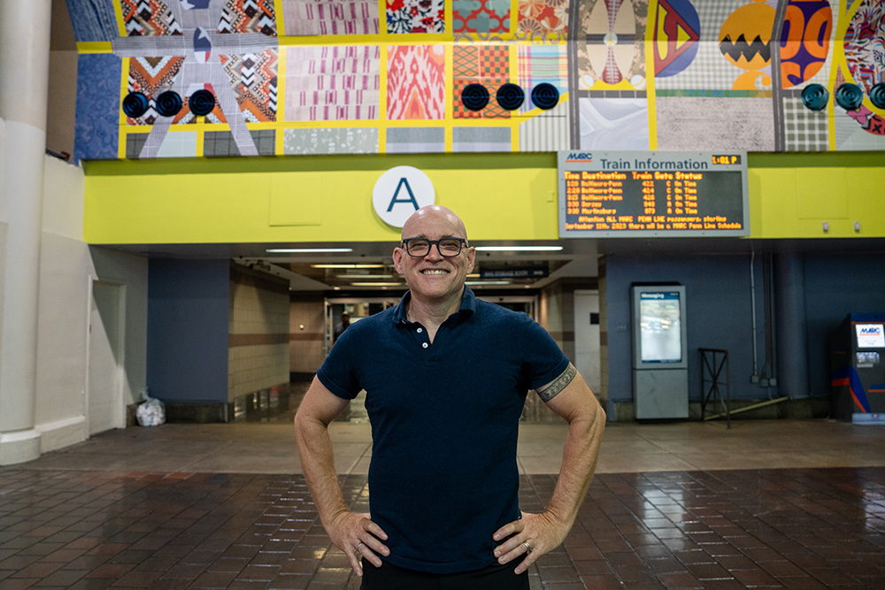 Artist Tim Doud stands in front of his digital print art installation in DC's Union Station