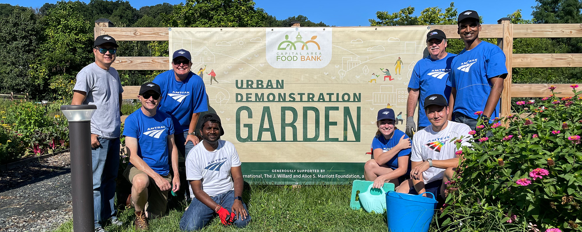 A group of volunteers smiles at a garden