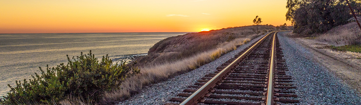 Train tracks along the coast at sunset.