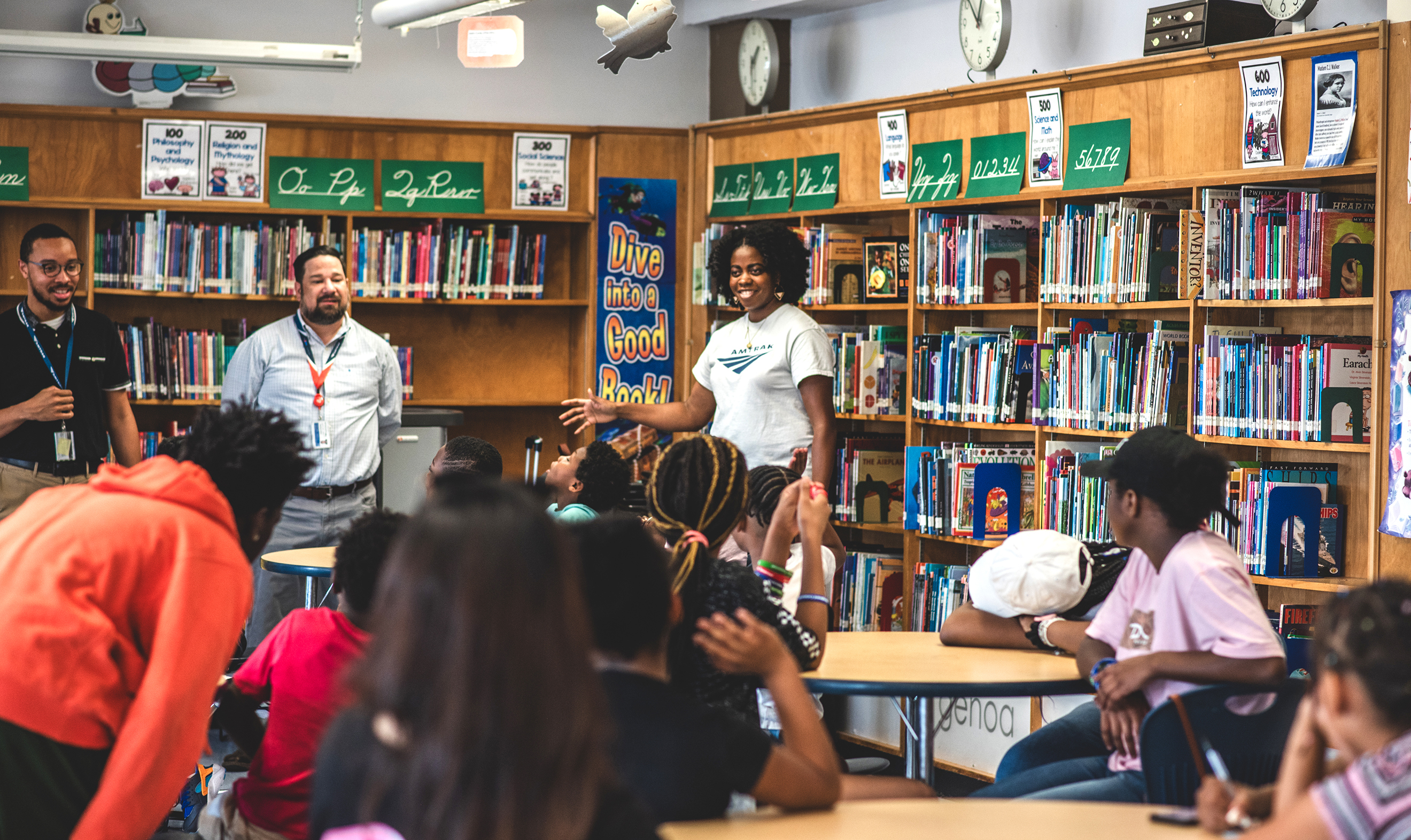 Amtrak employees talk to local students in a library