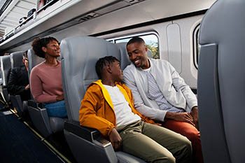 Boy sitting next to his father on board the train