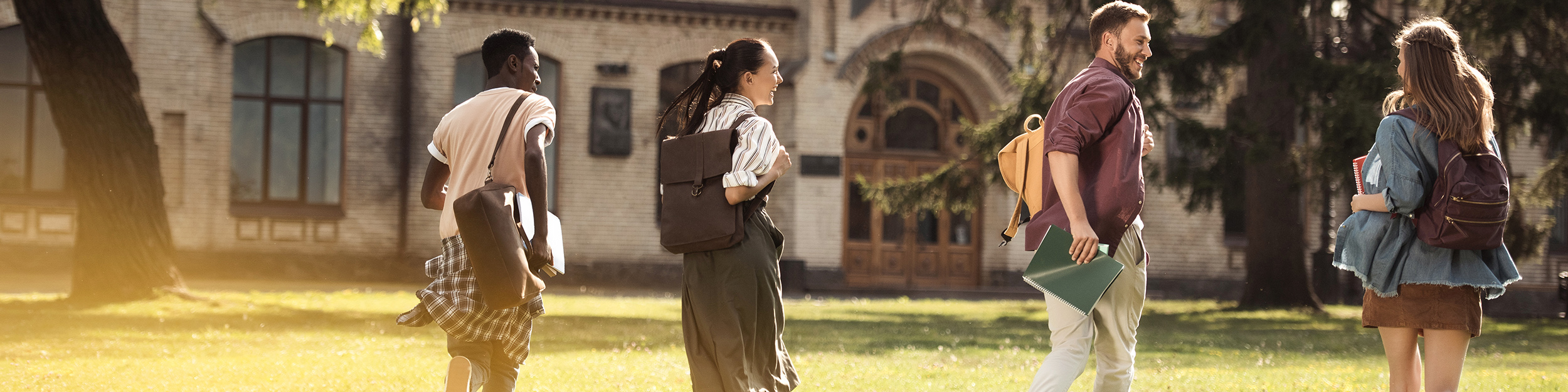 Quatre étudiants avec des sacs à dos courant vers l'entrée de l'école