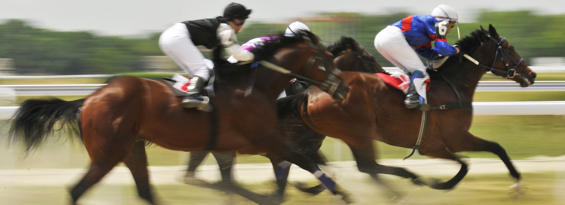 Racing jockeys and horses running on race track