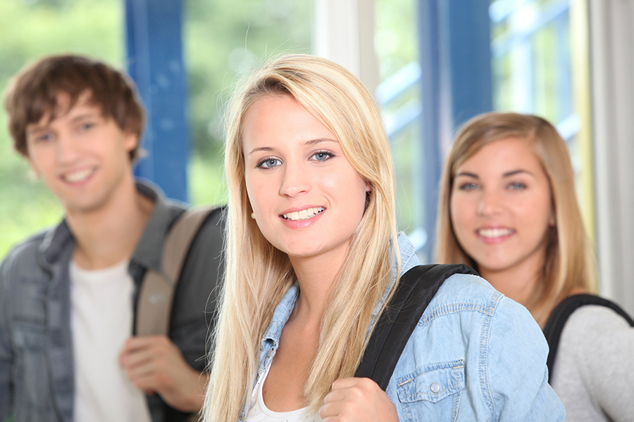 three students with backpacks smiling