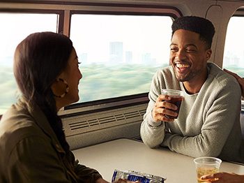 Tres pasajeros sentados a una mesa de cafetería de Amtrak, riendo