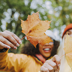 Two Ladies Hold Up Fall Leaves