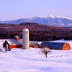 A red barn and silo surrounded by snow.