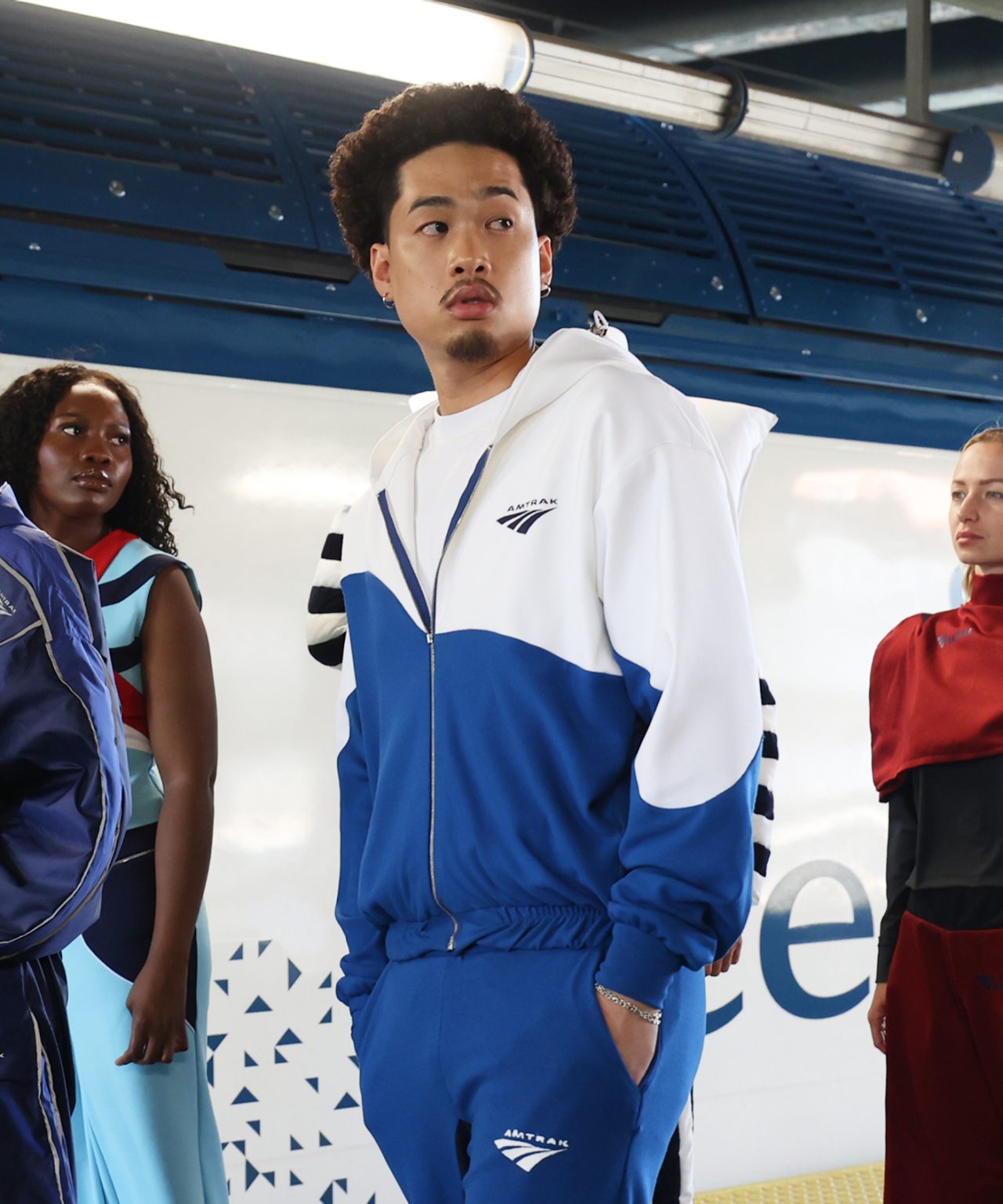 Student models blue and white tracksuit in front of train
