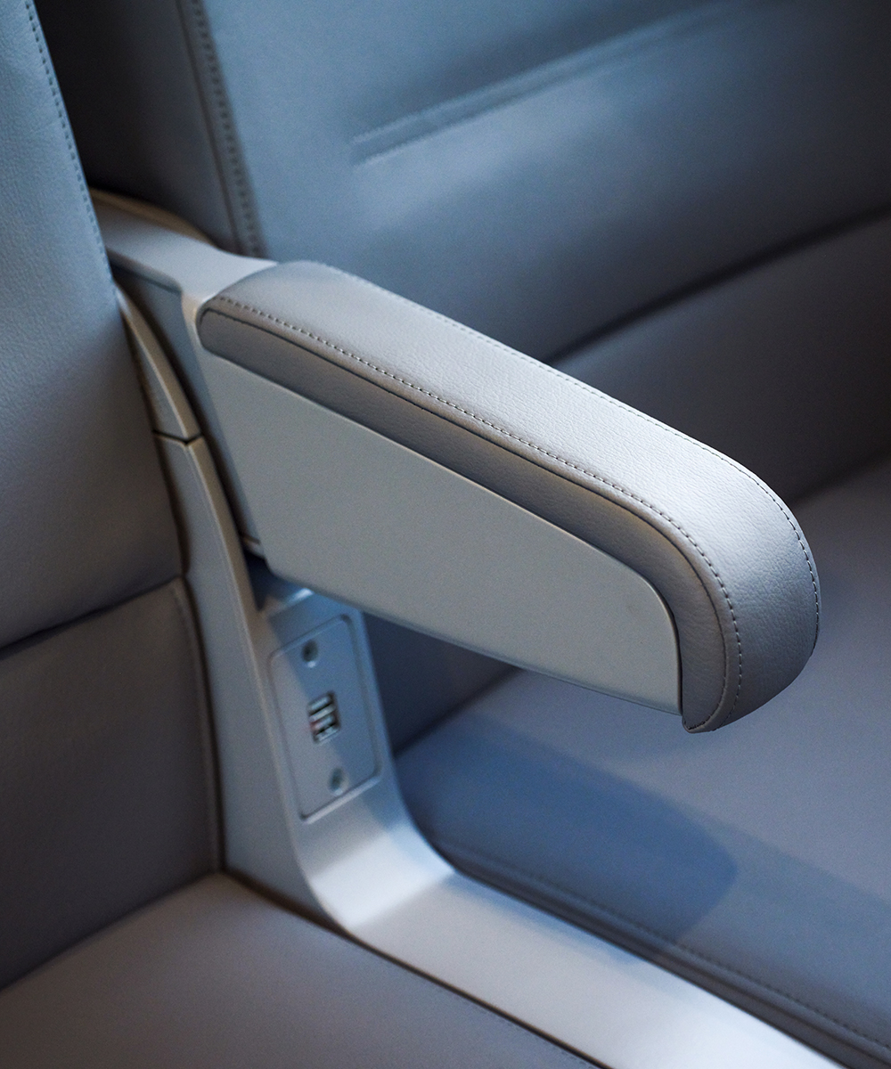 Blue and gray armrests and electrical plugs on Next Gen Acela 