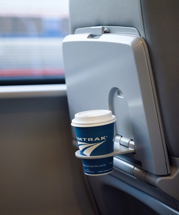  Amtrak to go coffee cup sits in a fold down cupholder on the back of a Next Gen Acela chair